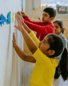 Children sticking crafts on a wall